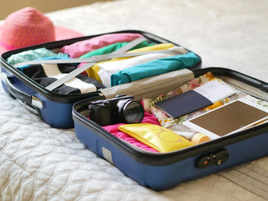 open suitcase on bed full of clothing and travel items