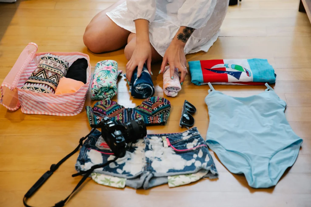 person kneeling on floor surrounded by packing cube and rolled clothing